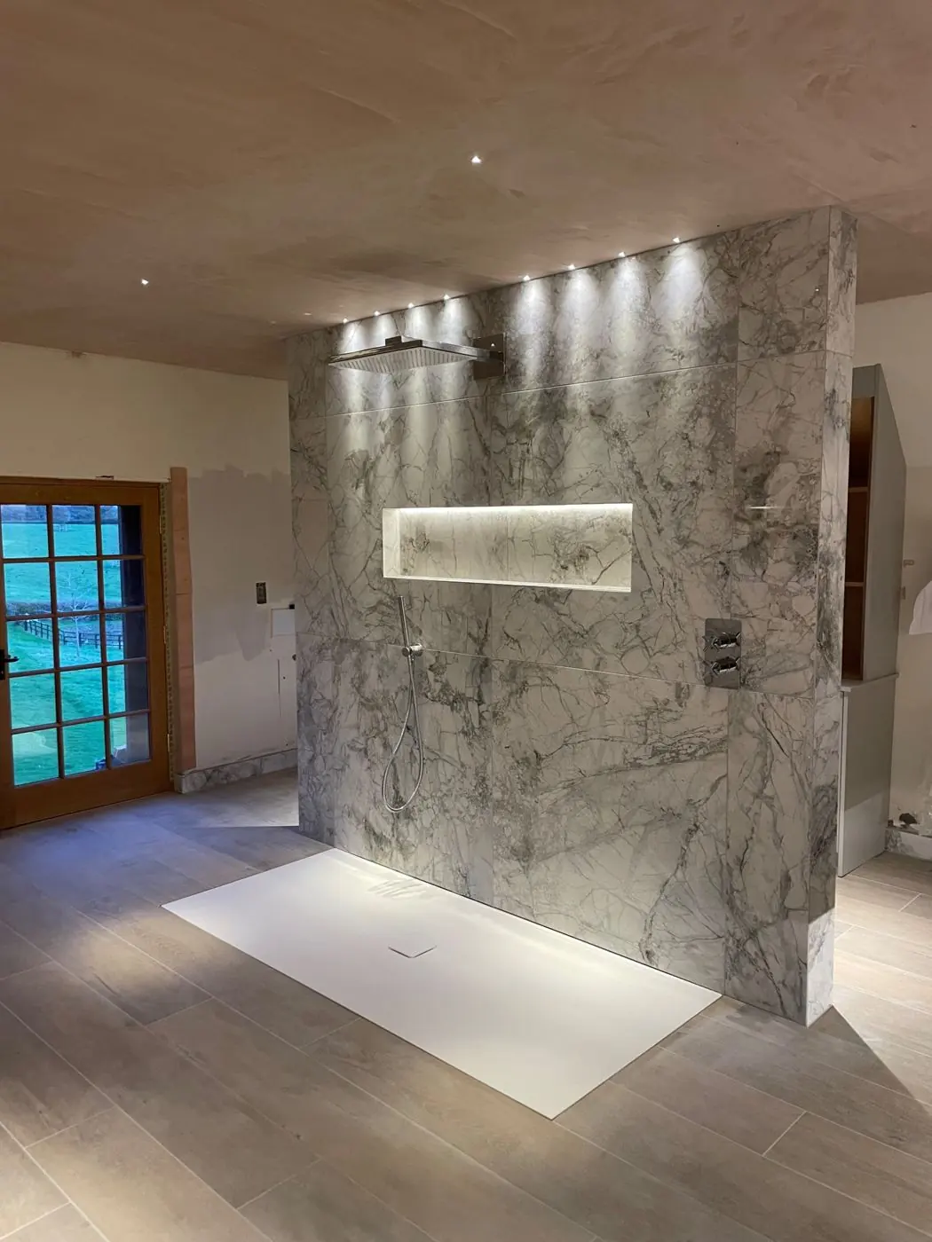 Finished tiled shower with recessed spotlights and illuminated niche