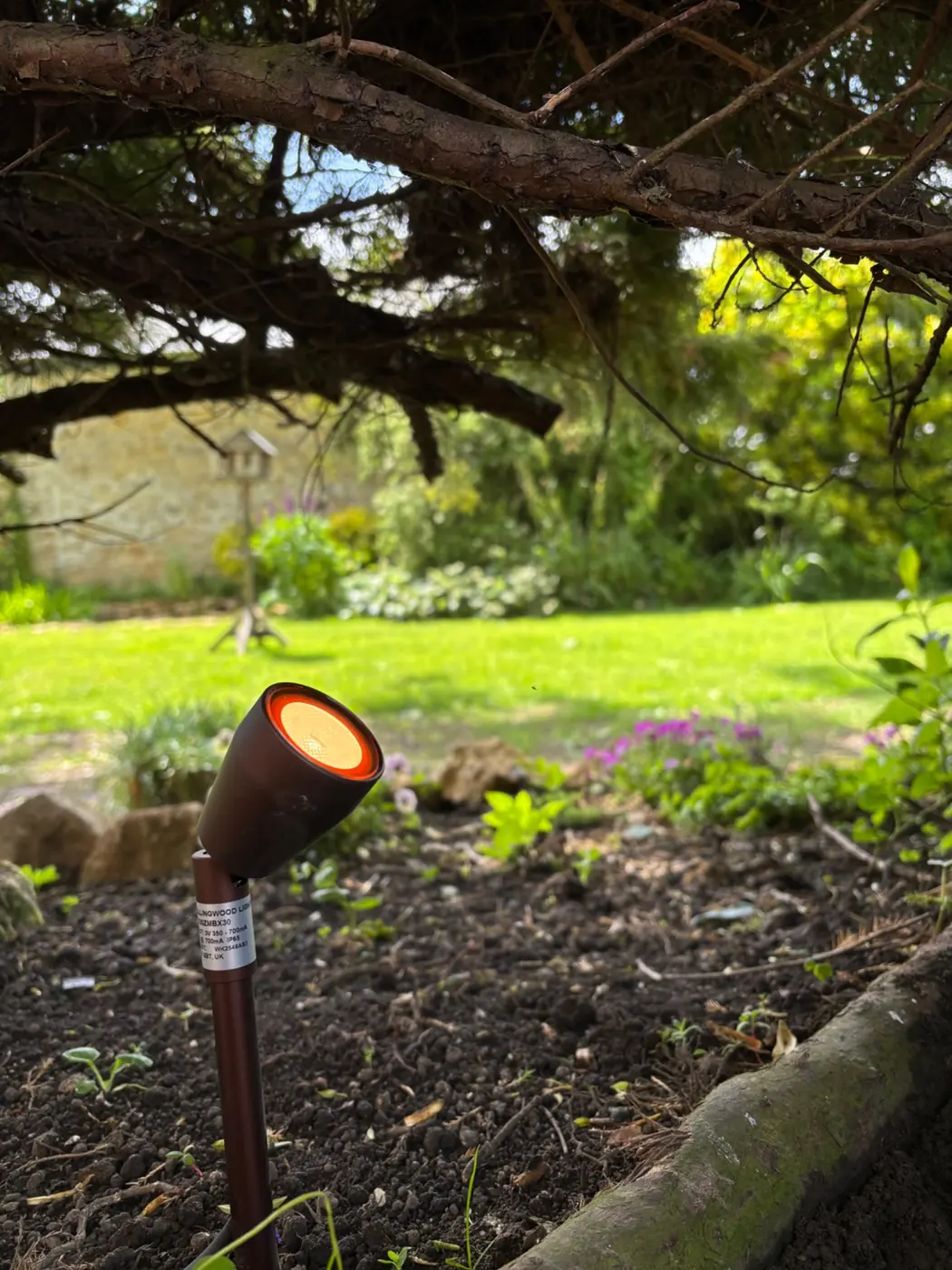 Garden spike light installed beneath mature planting