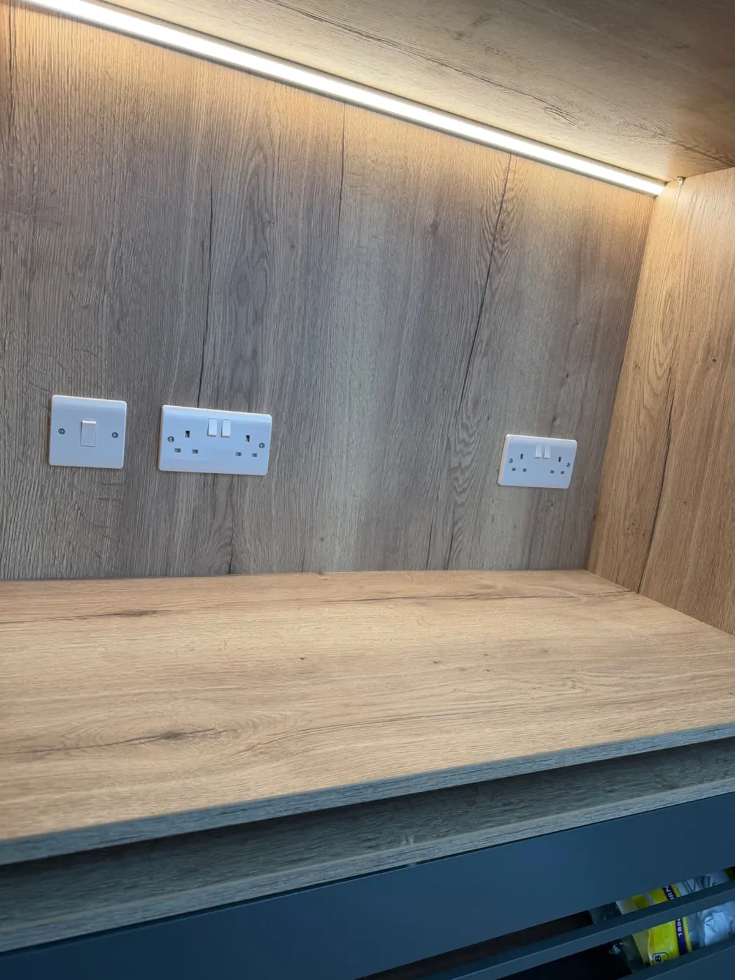 LED tape lighting installed above a fitted shelving and worktop area
